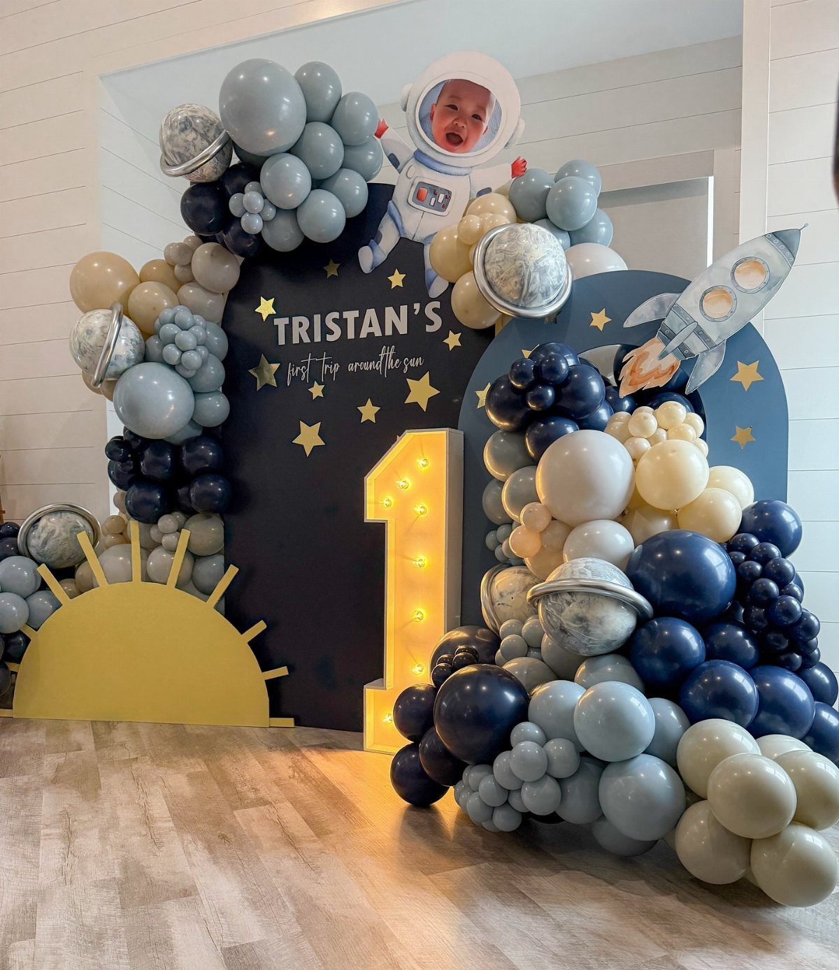 Space themed birthday backdrop with balloons, a glowing number one, and astronaut imagery.