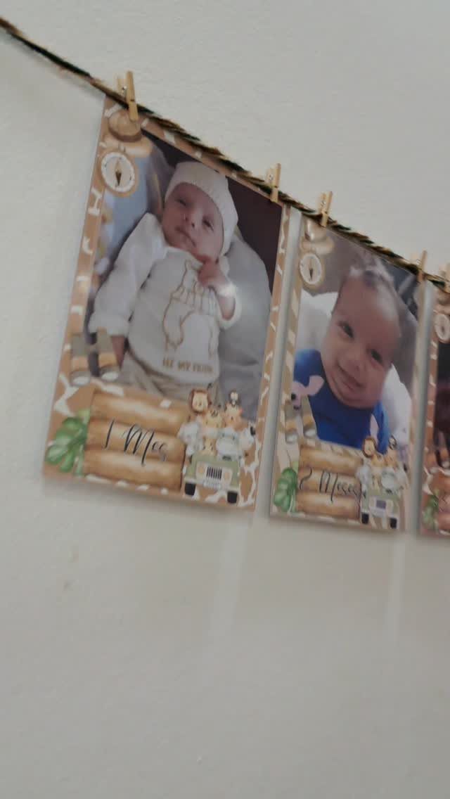Baby photos clipped to a string showing growth milestones for a first birthday.