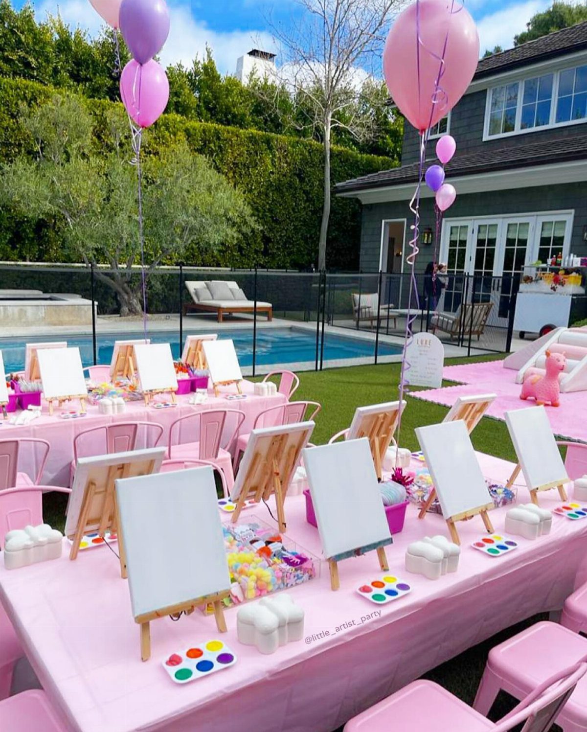 Pink party tables with small wooden easels, canvases, and paint palettes outdoors.