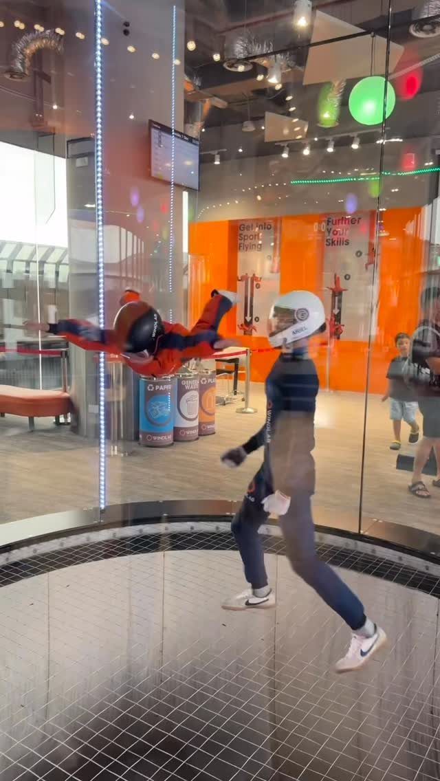 Person floating in a glass wind tunnel during an indoor skydiving experience.