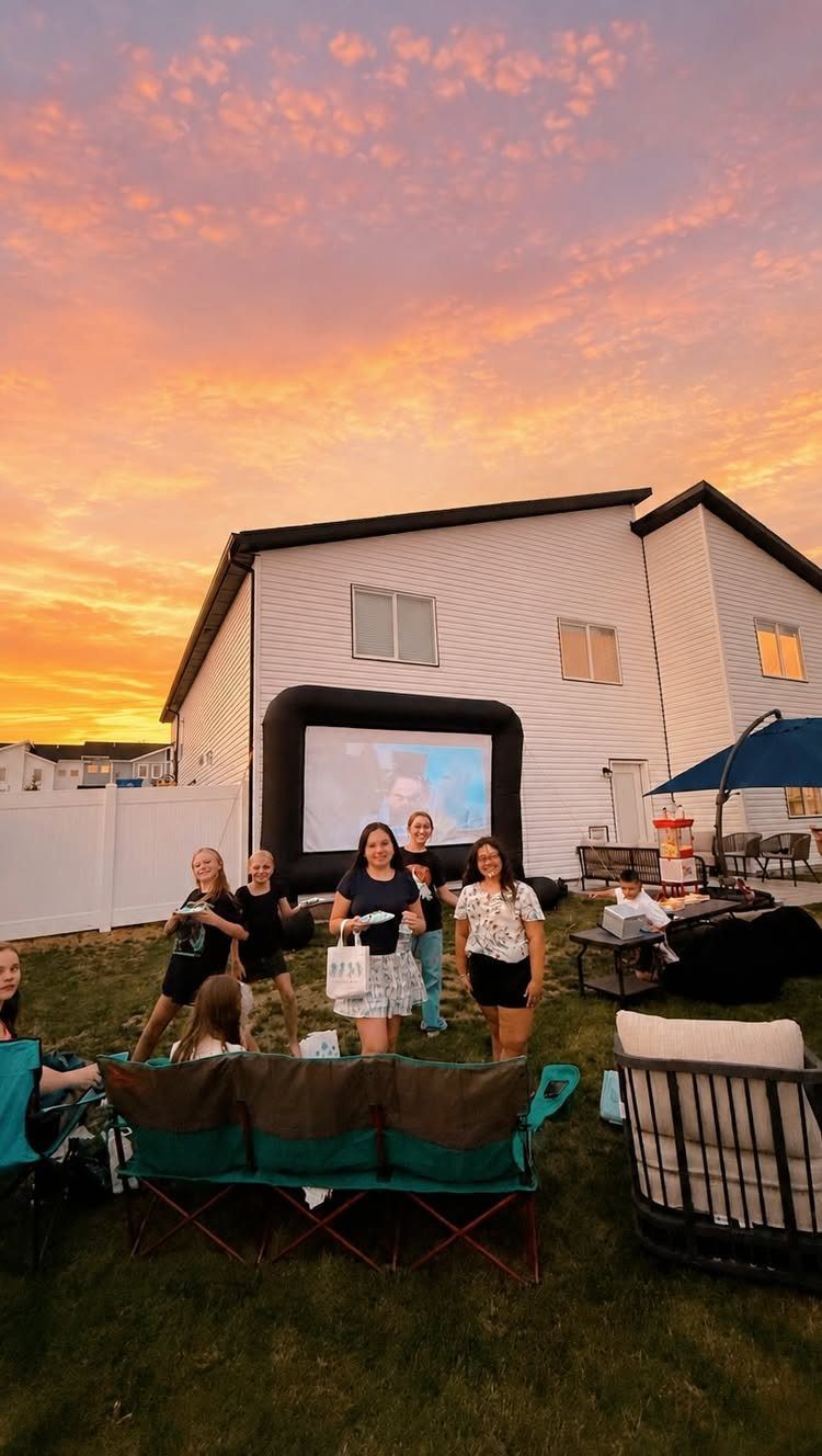 Young women standing in a backyard with a large inflatable outdoor movie screen.