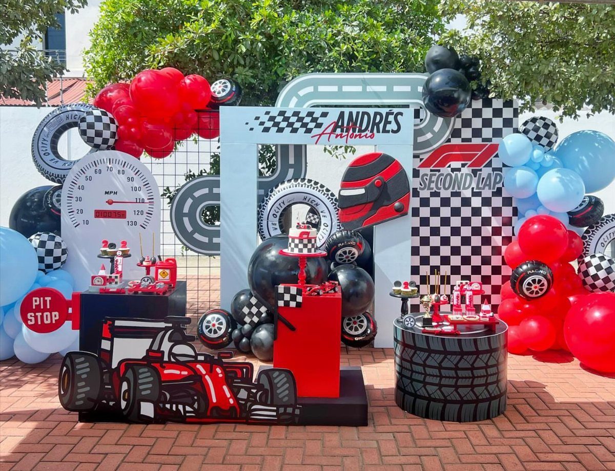 Racing themed party decorations with red balloons, checkered flags, and F1 car cutouts.