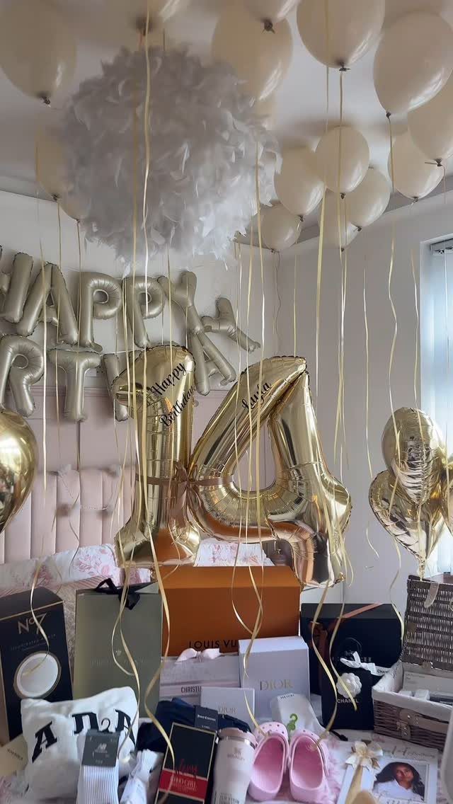Gold number 14 balloons and birthday decorations with gifts on a bed