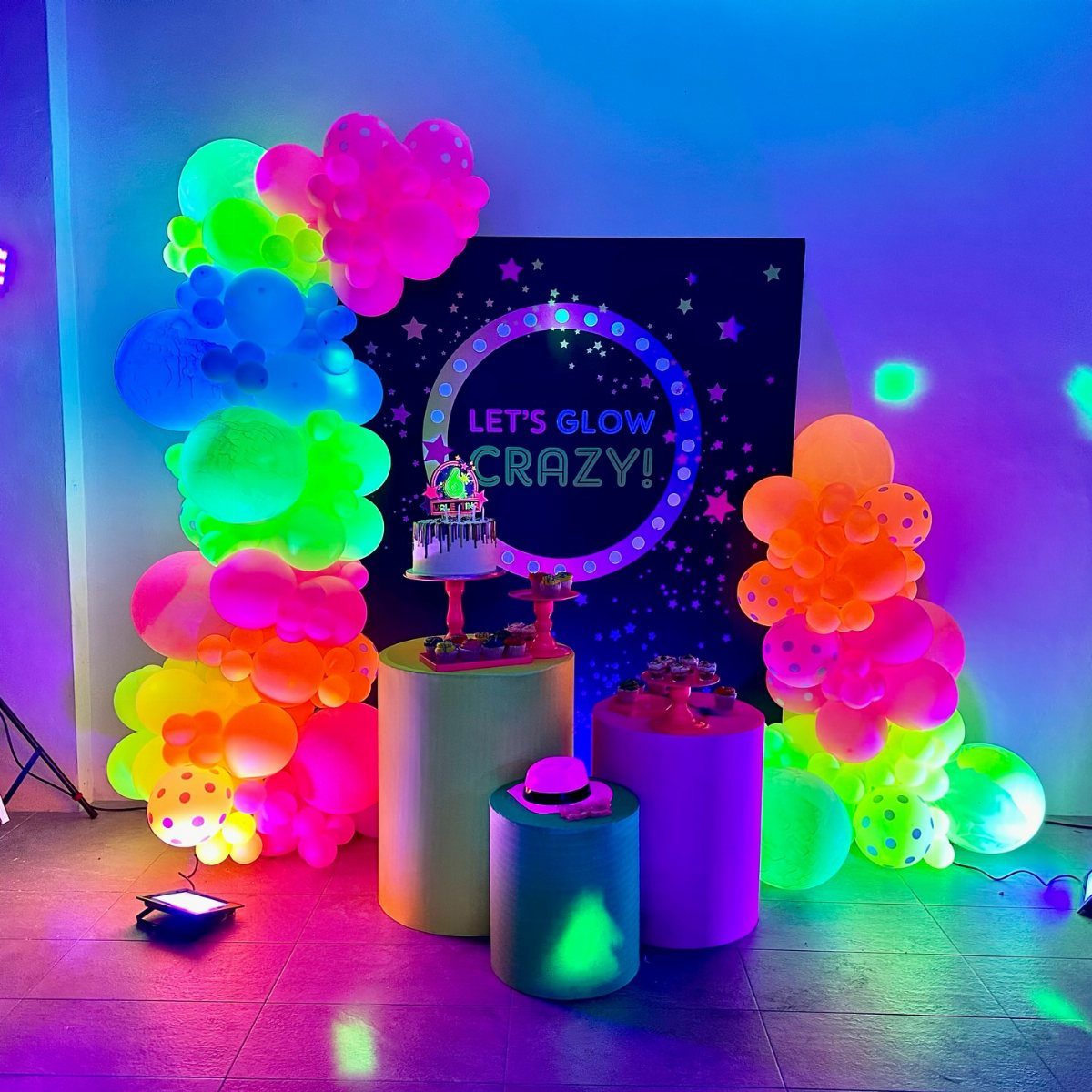 Neon balloon arches and glowing decorations for a glow-in-the-dark birthday party setup.