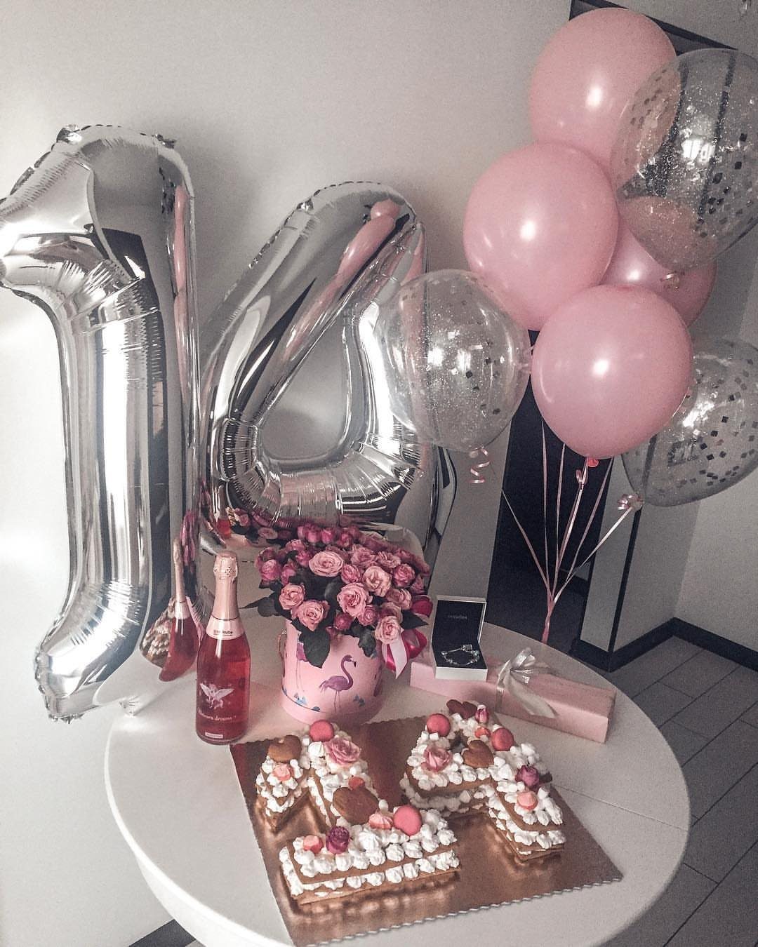 Number 14 cake, pink roses, and silver balloons on a white party table.