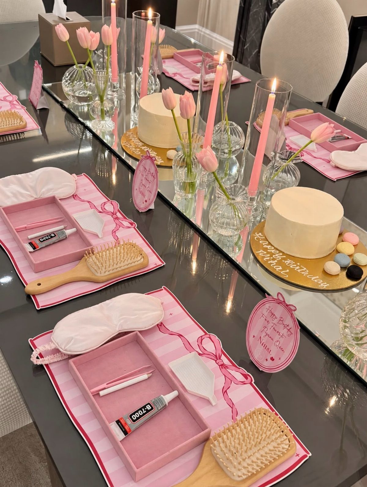 Pink party table settings with hairbrushes, sleep masks, and small cakes with tulips.