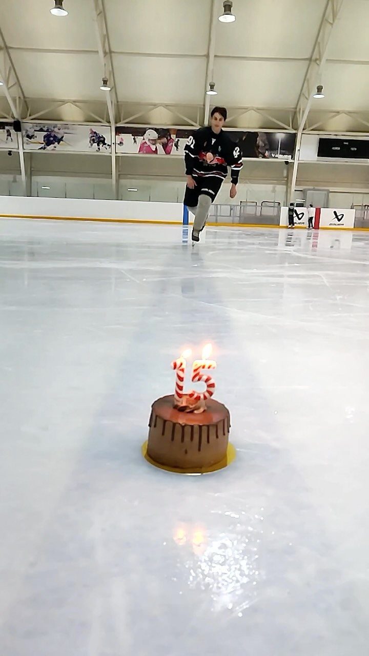 Chocolate cake with 15 candles on an ice rink with a hockey player