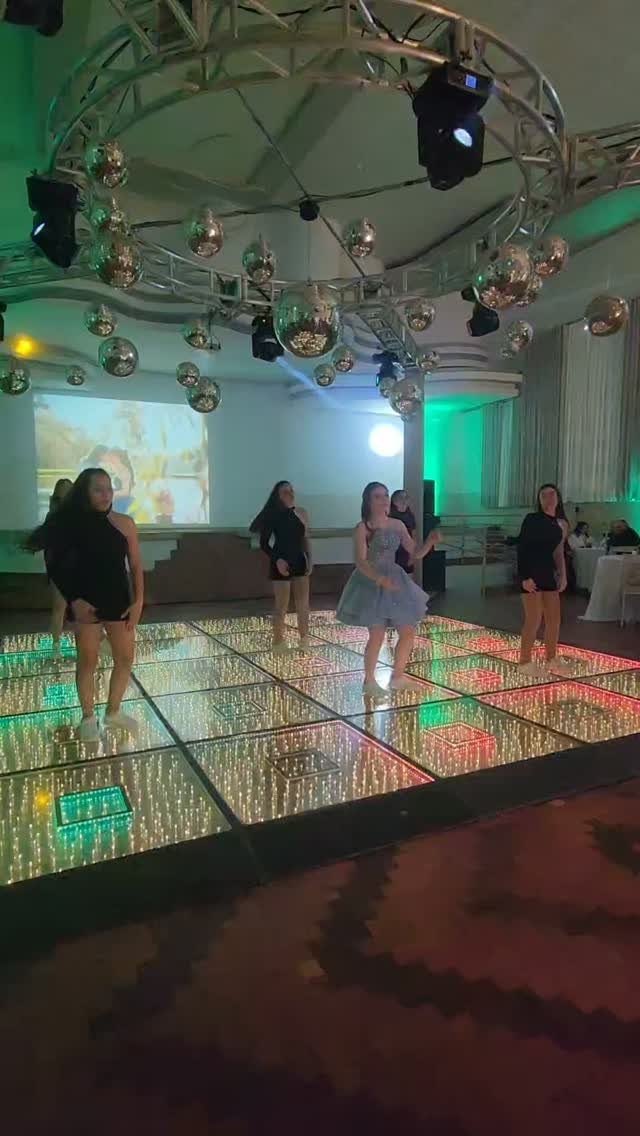Teenage girls dancing on a glowing LED dance floor under disco balls