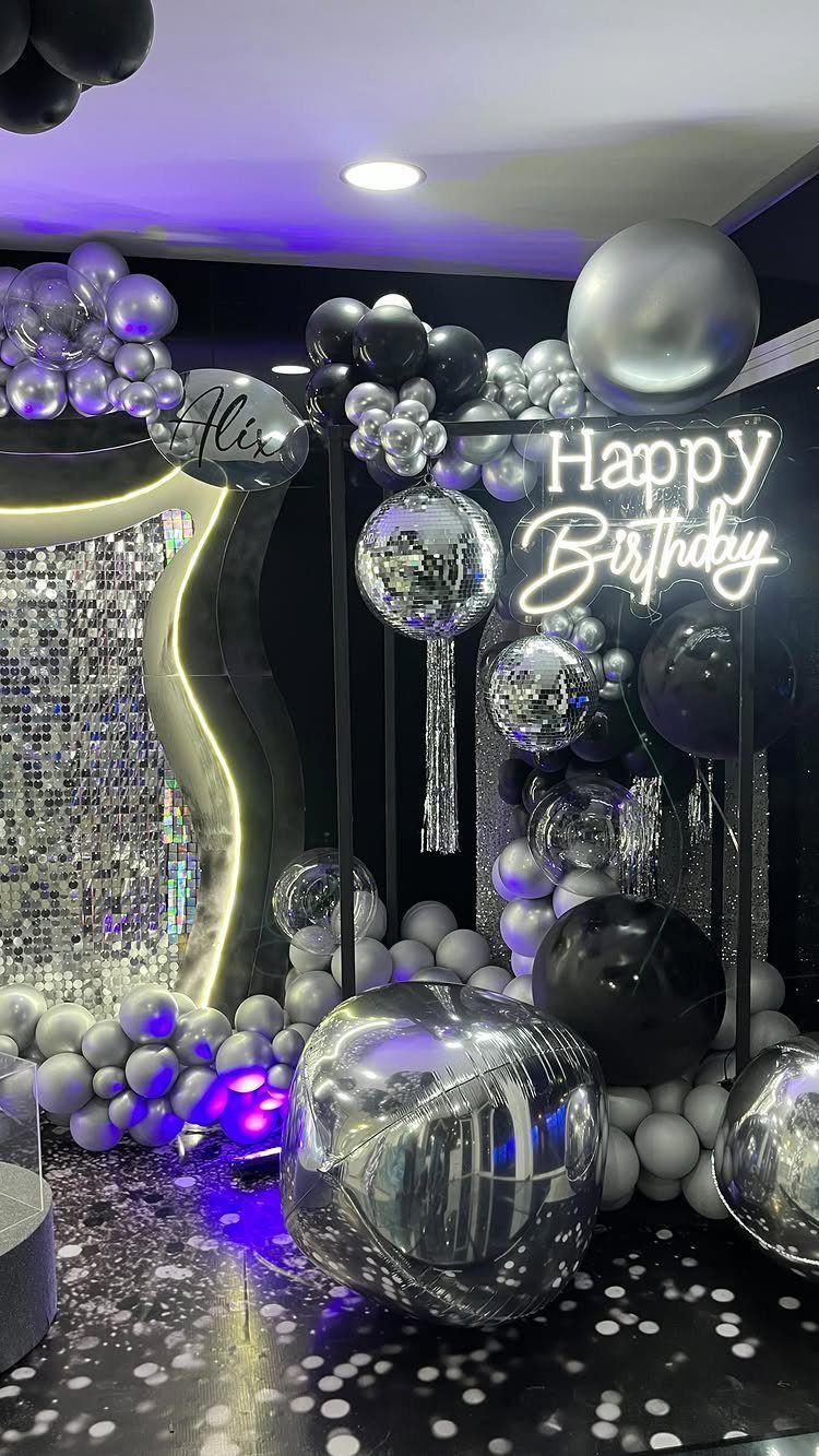Silver and black balloon decorations with a neon Happy Birthday sign and sequin backdrop.