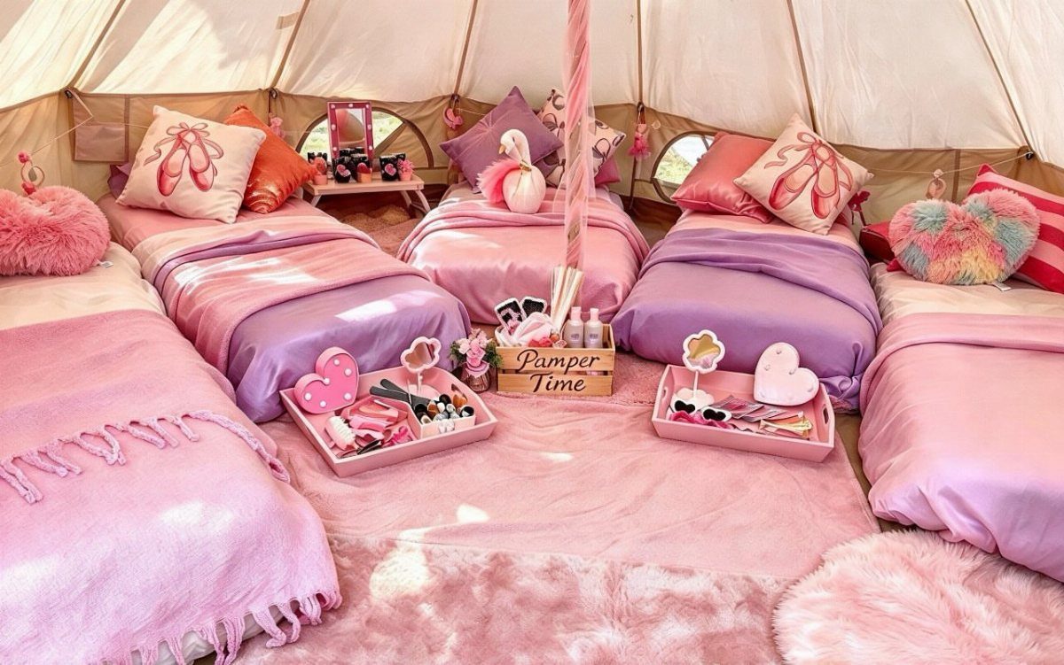 Four pink and purple beds arranged inside a white tent for a slumber party