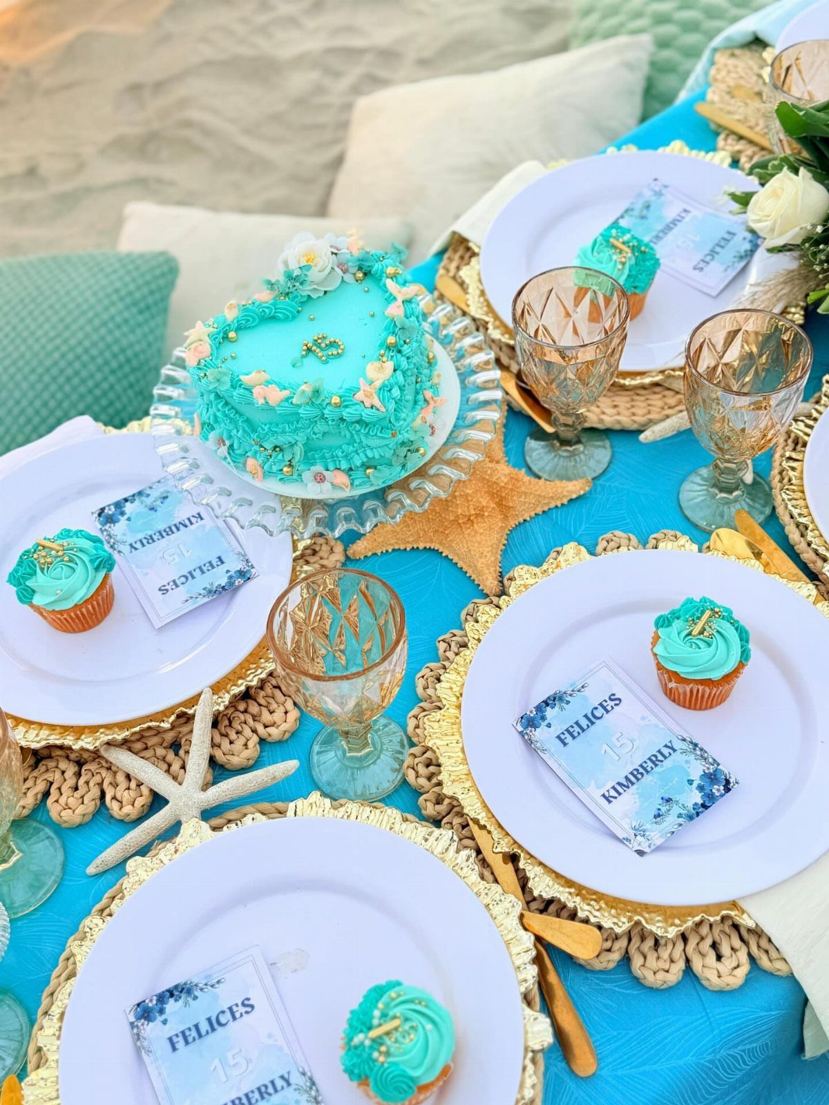Turquoise birthday table setting with a cake, cupcakes, and starfish decorations for Kimberly.