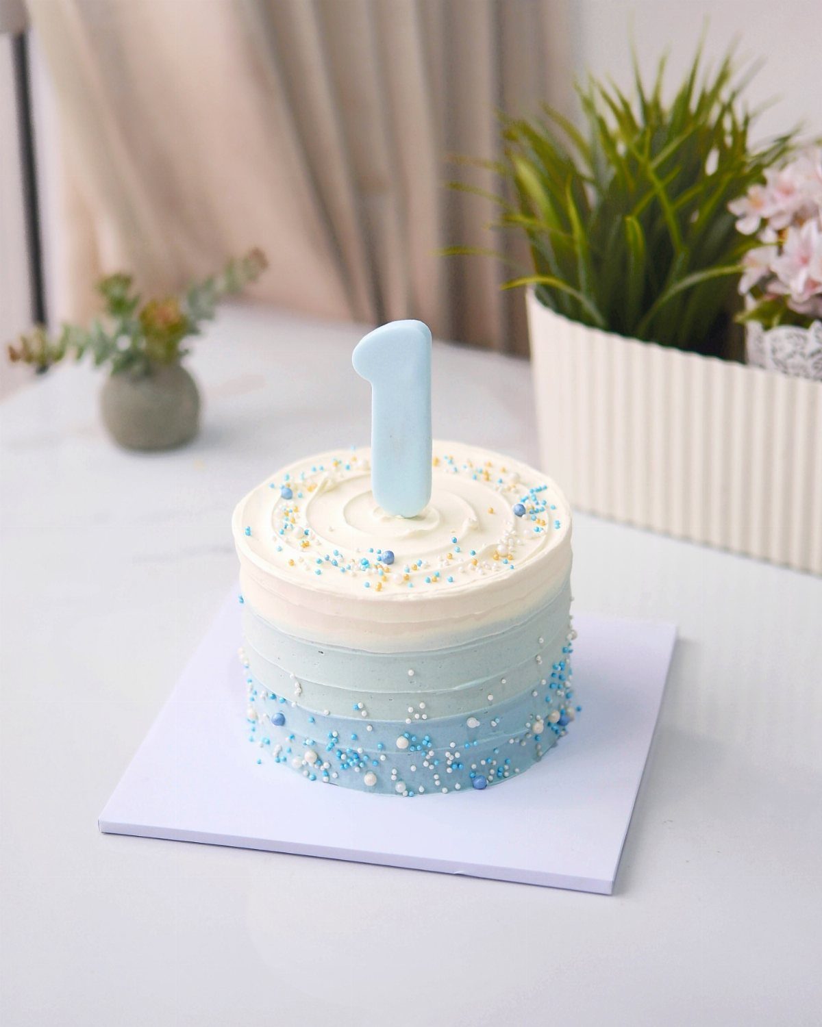 Small ombre blue and white birthday cake with a number one candle.