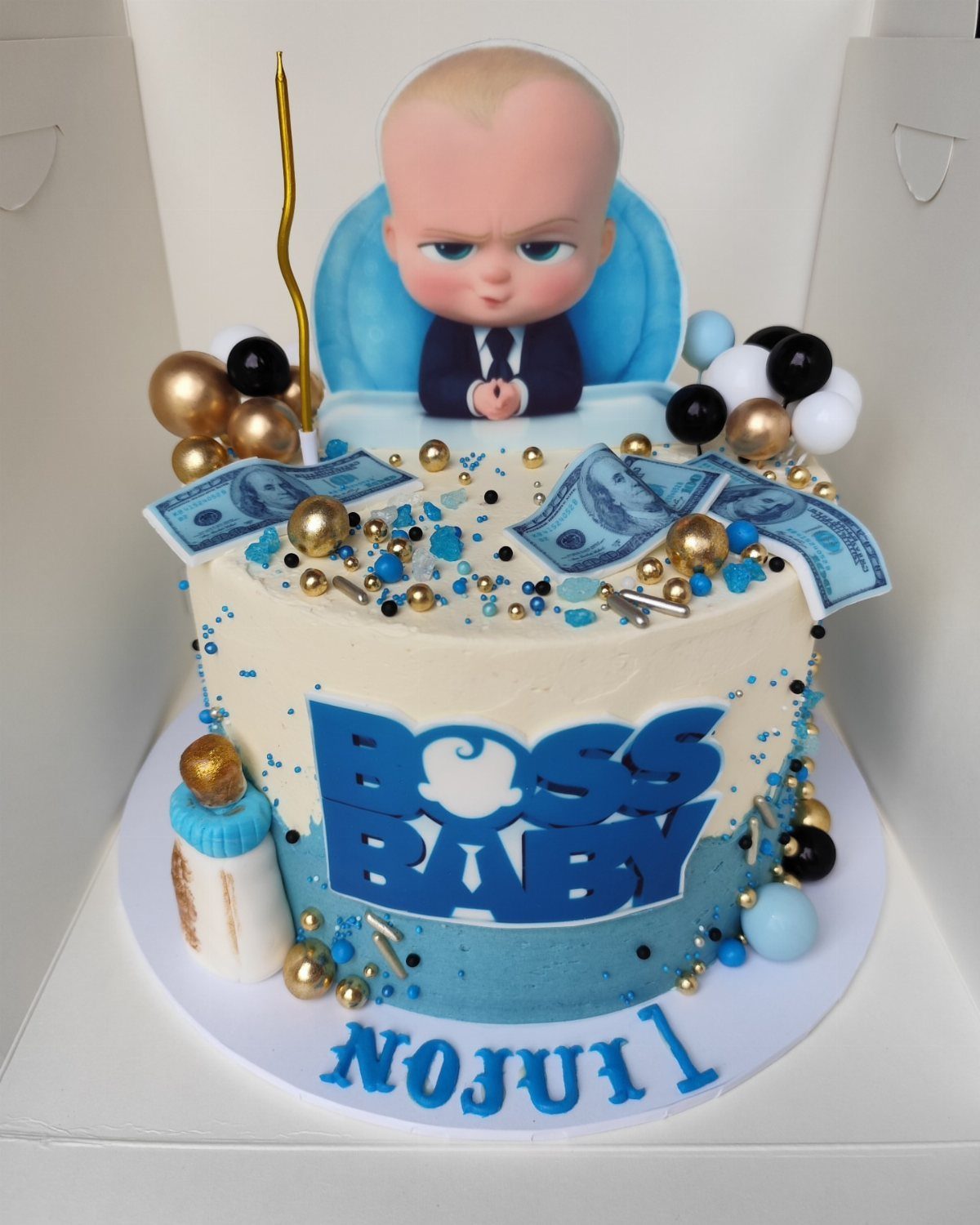 Boss Baby themed birthday cake with blue frosting, gold pearls, and edible money.