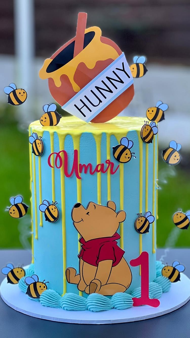 Winnie the Pooh themed birthday cake with blue frosting, honey pot, and bees.