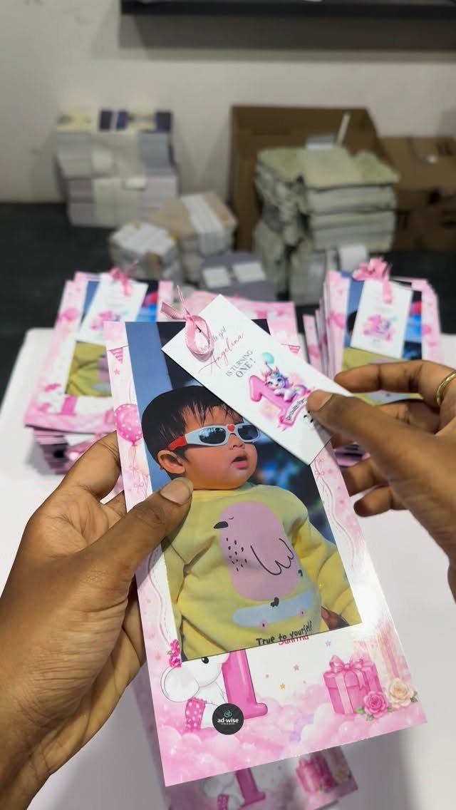 Pink first birthday invitation with a baby photo and artistic decorative elements.