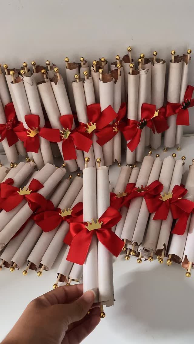 Rolled white paper scrolls tied with red bows and gold crown charms.