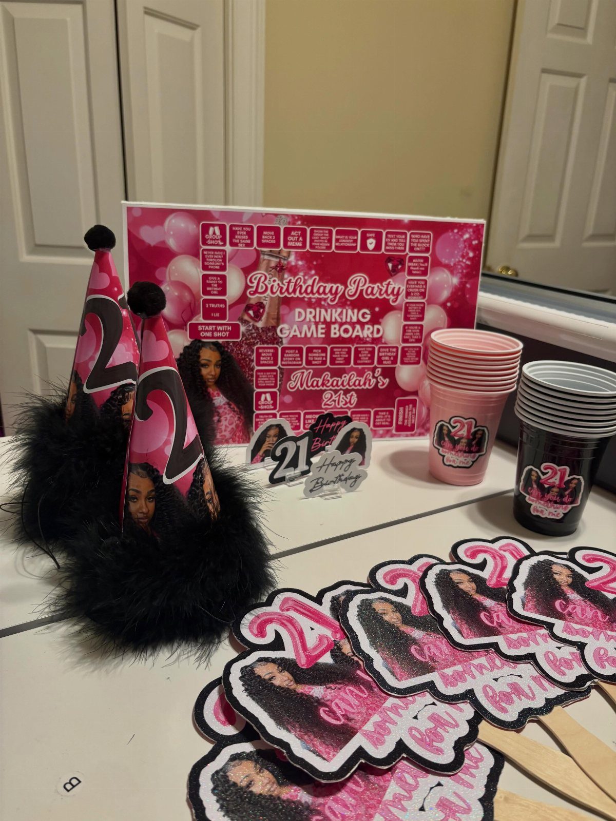 Birthday party supplies including a drinking game board, party hats, and themed cups.