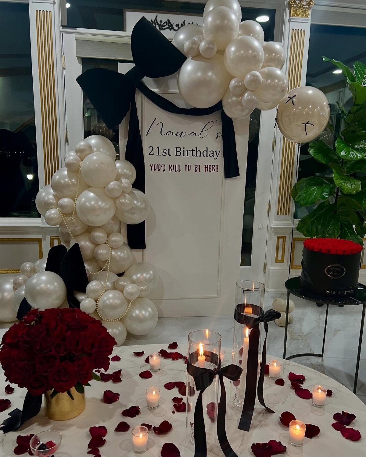 Birthday party decoration with white balloons, red roses, and a murder mystery sign.