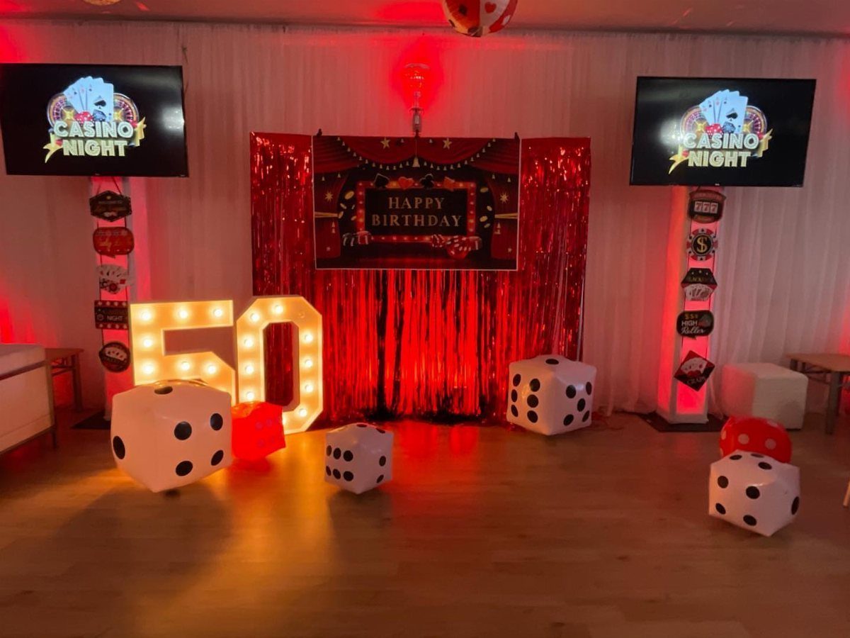 Casino night birthday party setup with giant dice and glowing number 50.