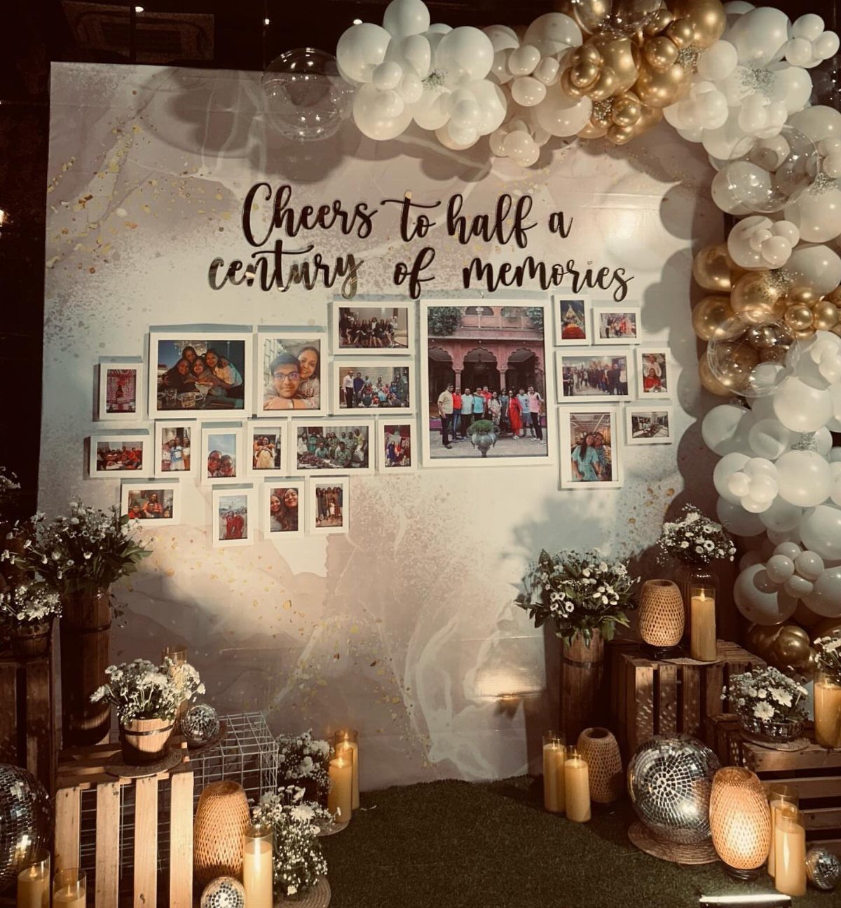 Celebratory backdrop with gold balloons, framed photos, and candles for a 50th birthday.