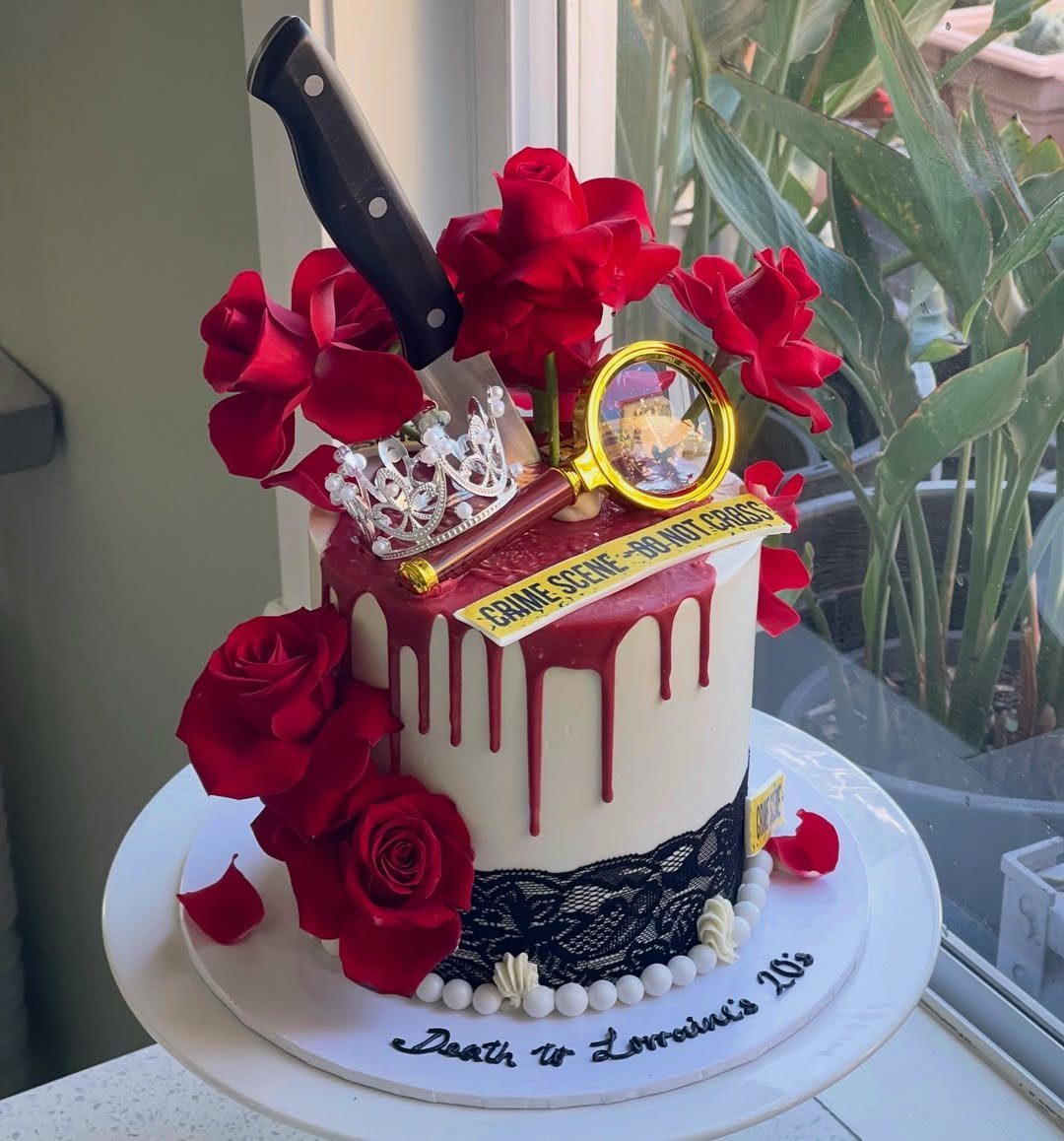 Crime scene themed cake with red roses, a knife, and a magnifying glass.