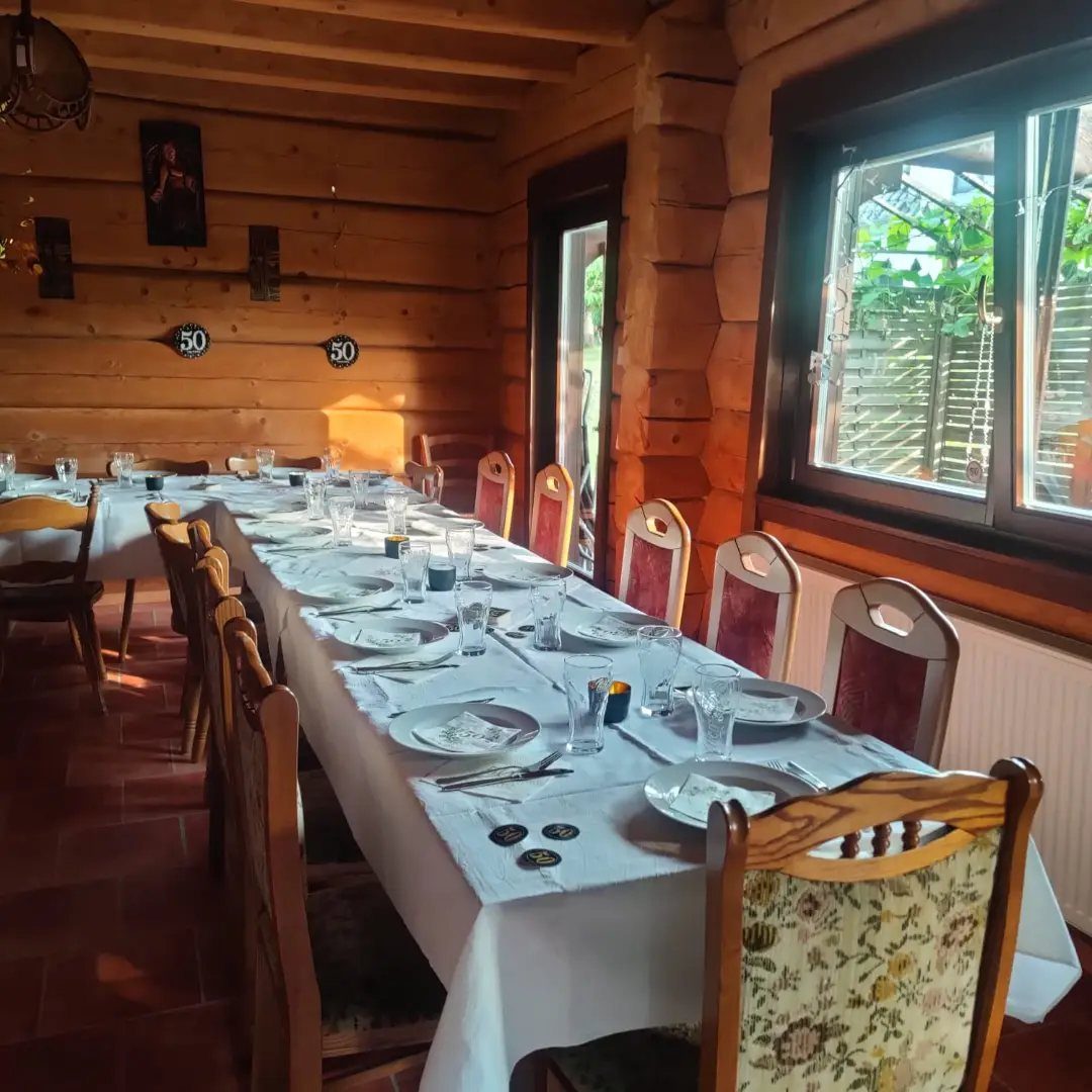 Dining table set for a party inside a rustic wooden log cabin interior.