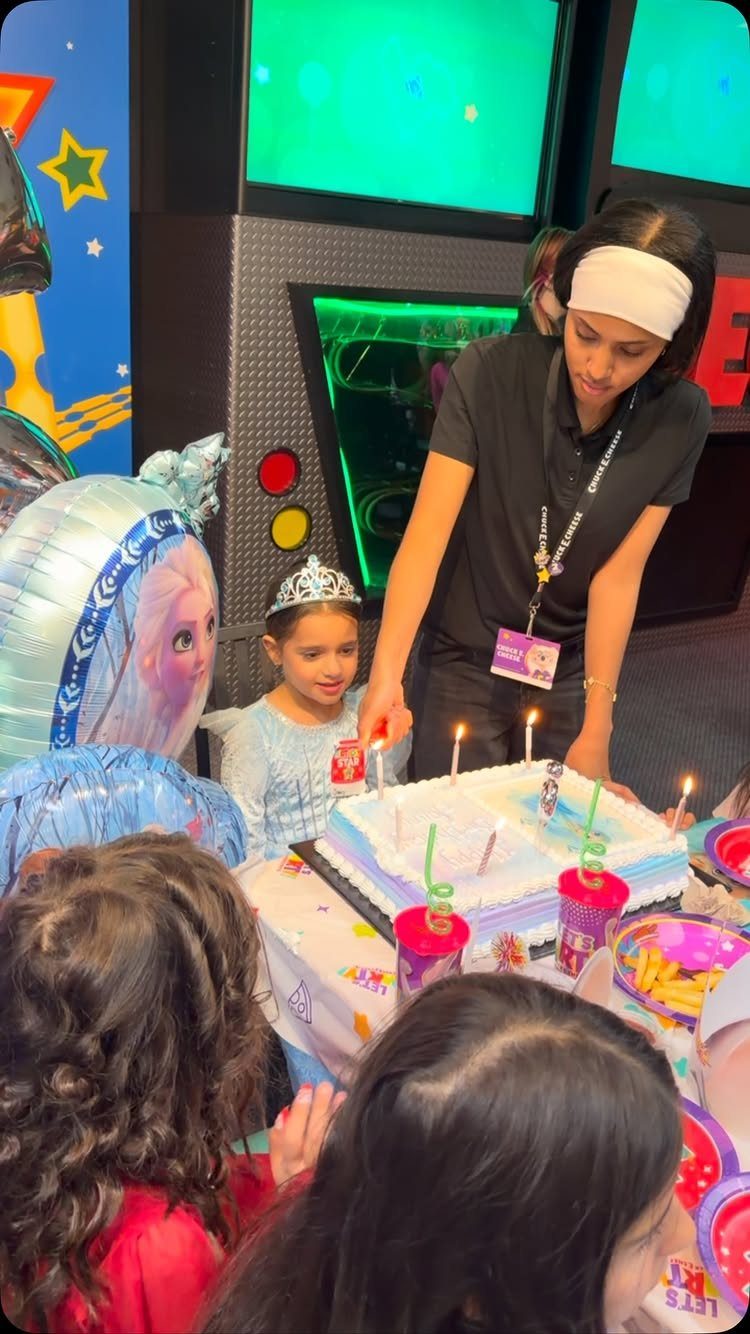 Young girl with a tiara celebrating her birthday with a cake and balloons.