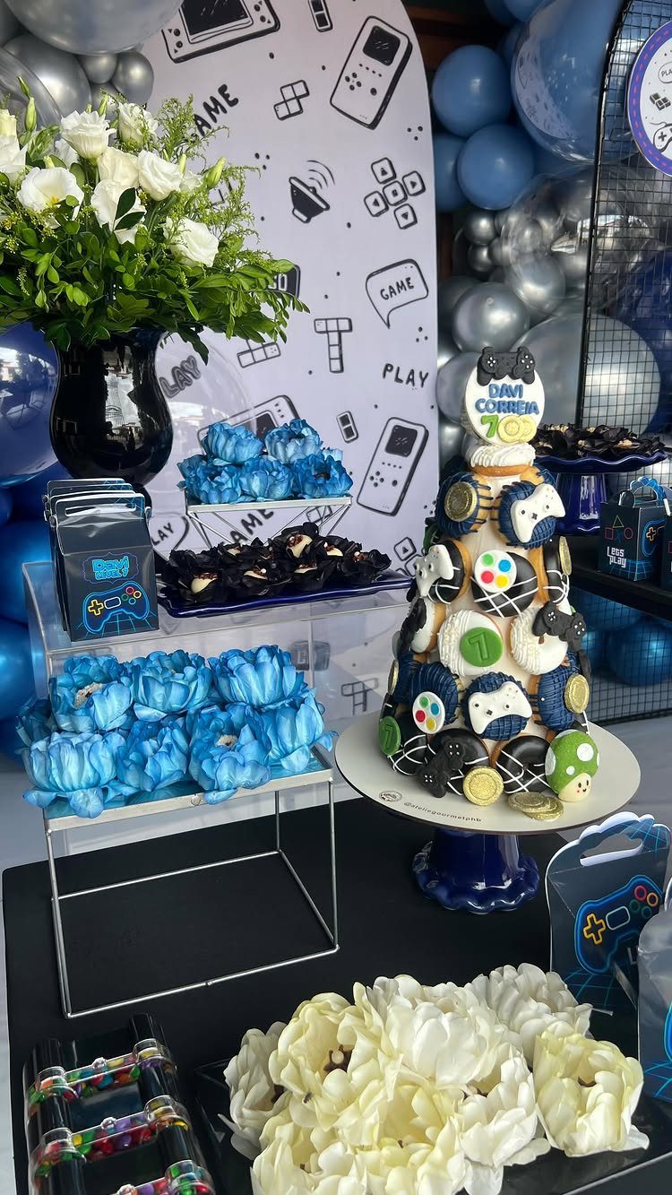 Gaming themed party table with a decorated cake, blue cupcakes, and controller backdrop.