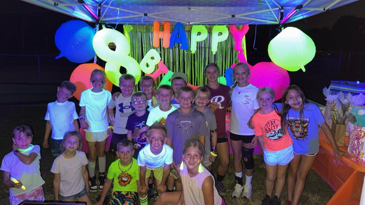 Children posing at a night birthday party with glowing balloons and neon accessories.
