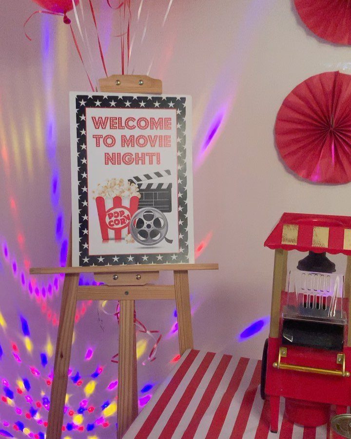 Movie night sign on a wooden easel next to a red popcorn machine.