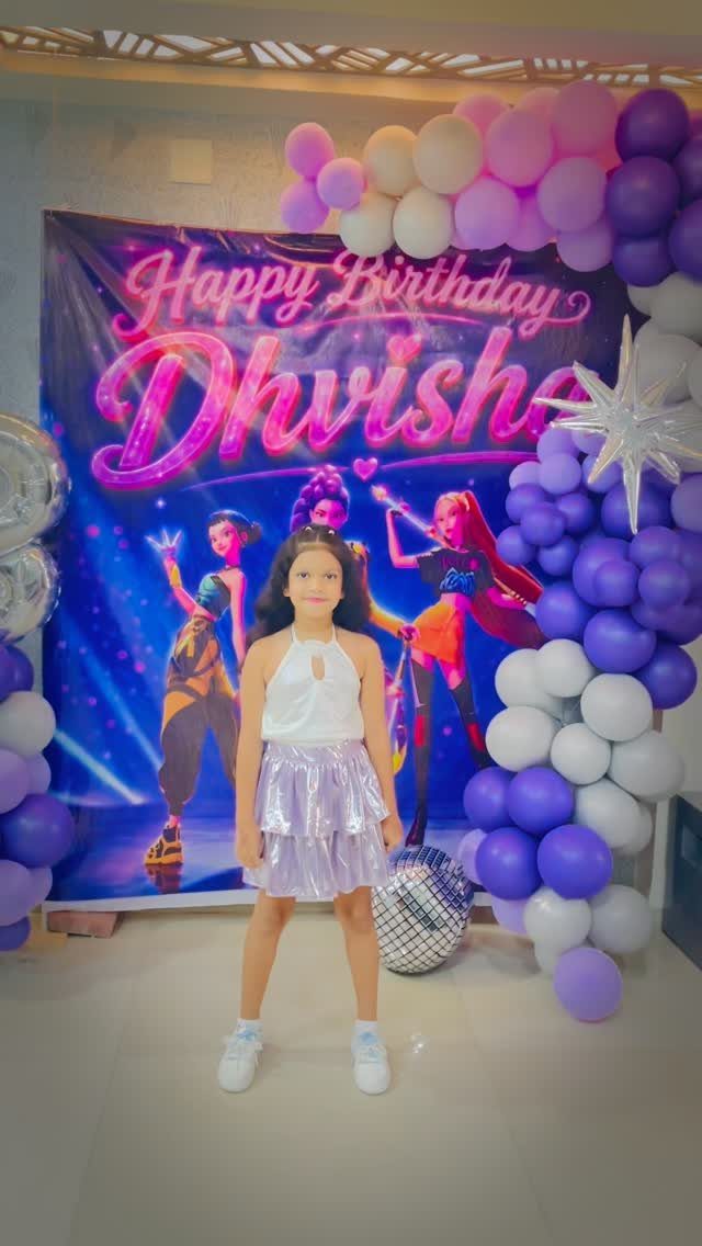 Girl in purple skirt posing before a dance themed birthday backdrop with balloons.
