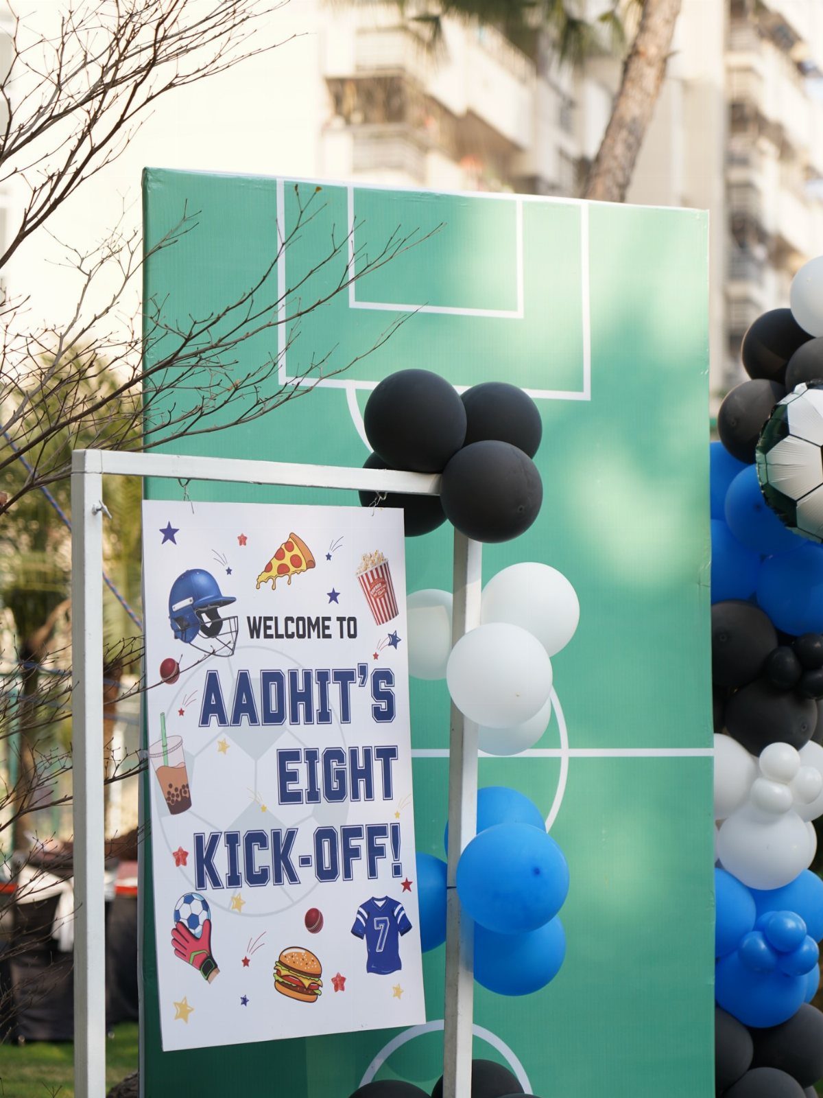 Sports themed birthday party backdrop with soccer field design and blue and black balloons