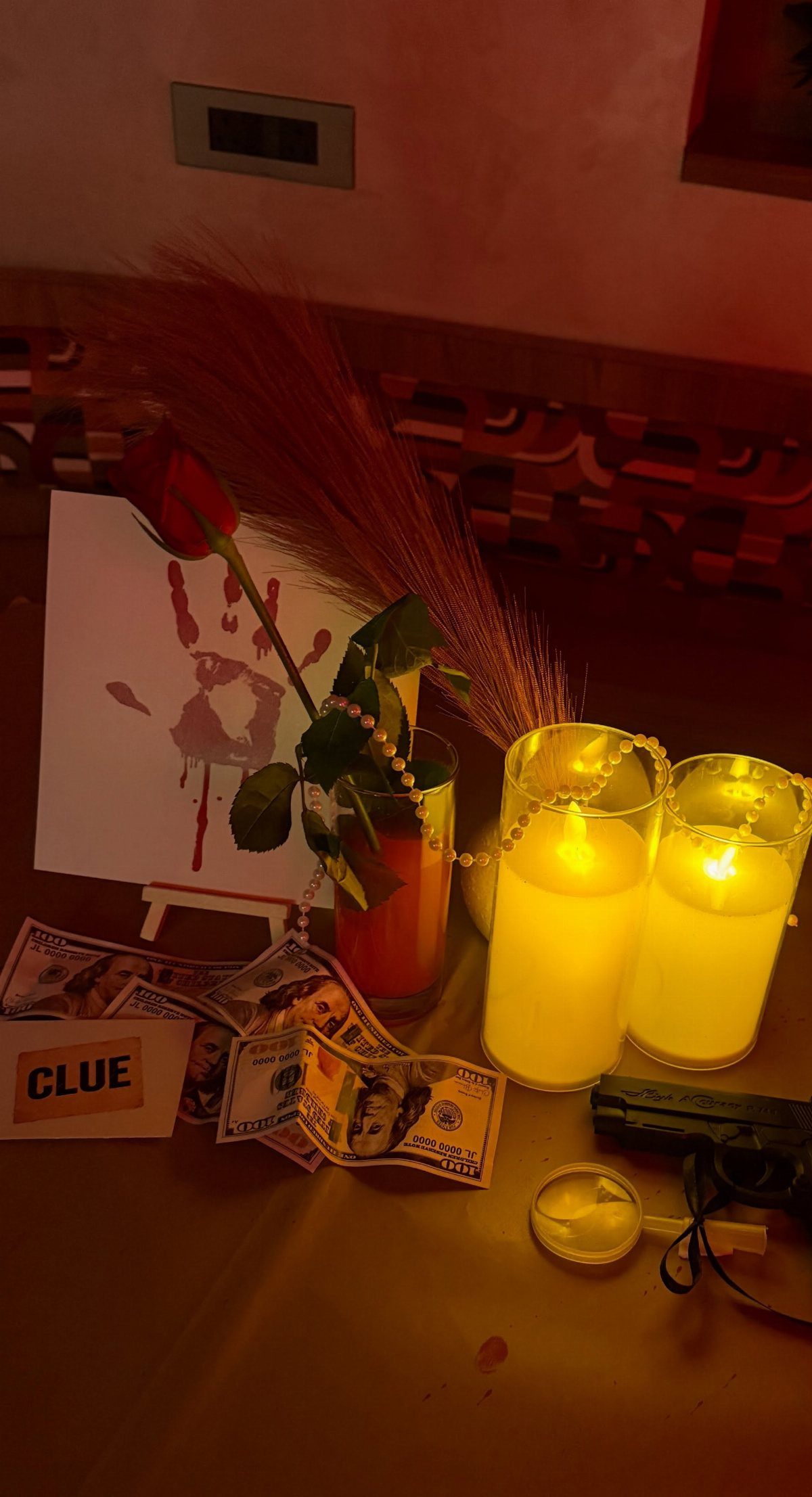 Murder mystery dinner setup with a red rose, candles, magnifying glass, and clue card.