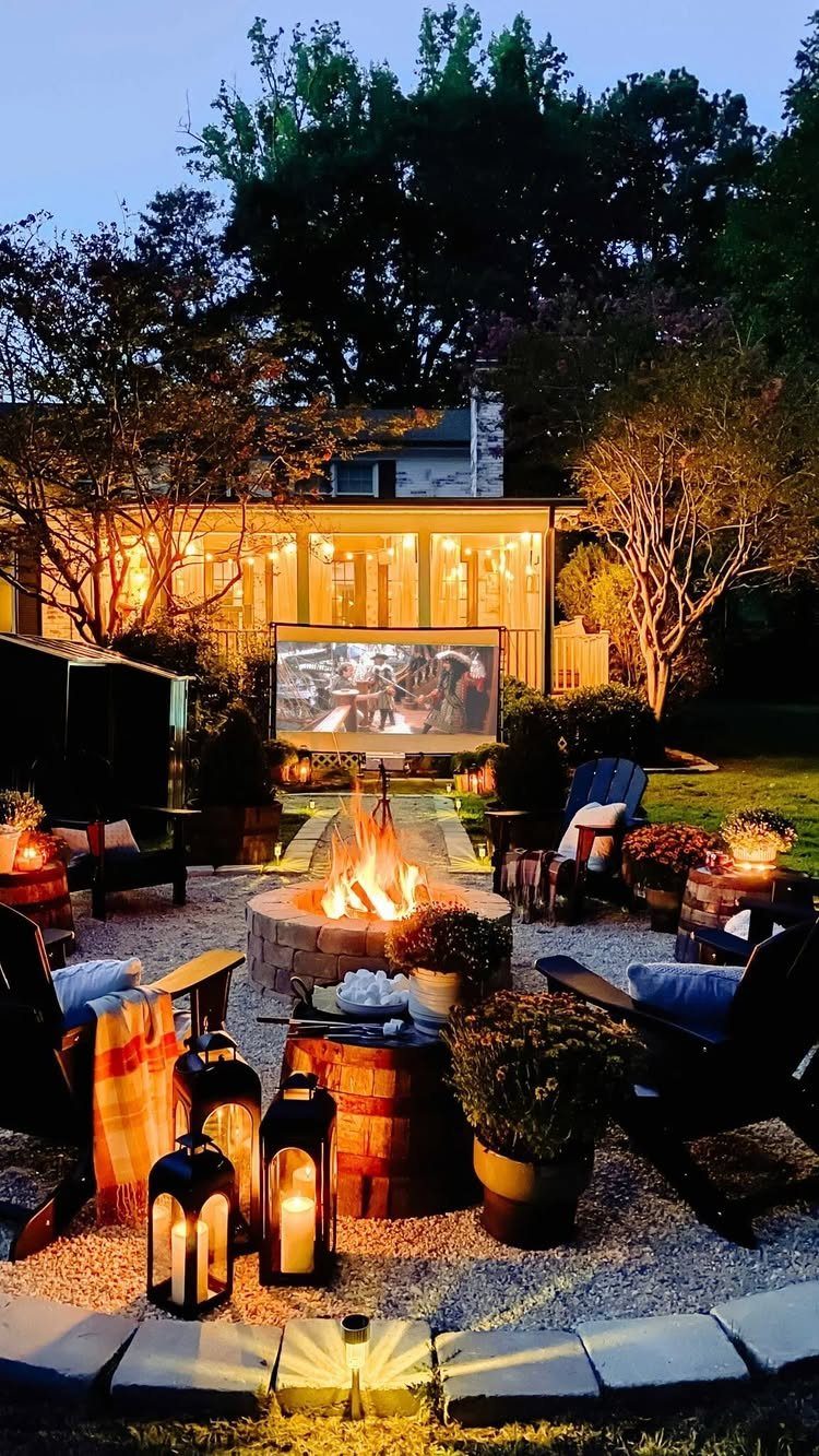 Outdoor movie screen and fire pit with cozy seating and lanterns at twilight.