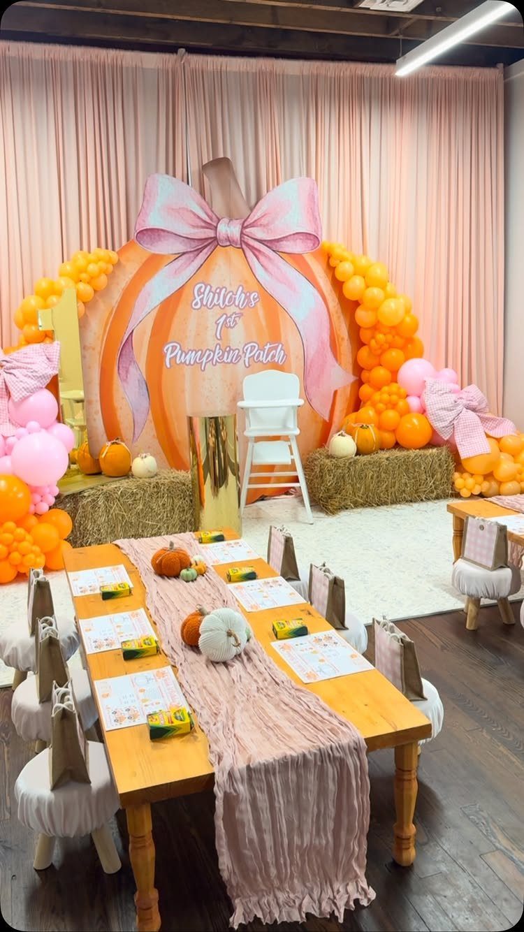 Birthday party setup with pumpkin backdrop, orange balloons, and a decorated wooden table.