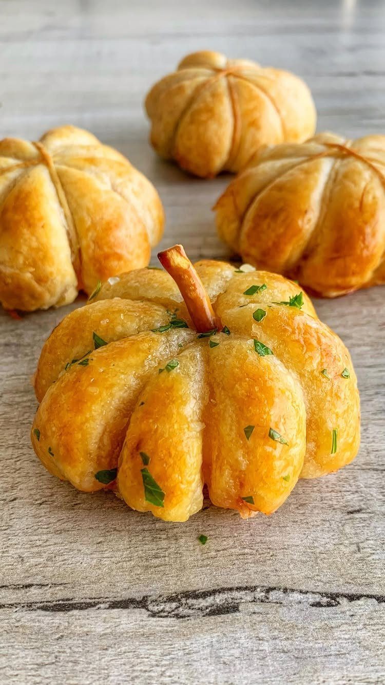 Pumpkin shaped bread rolls with parsley on a rustic wooden table