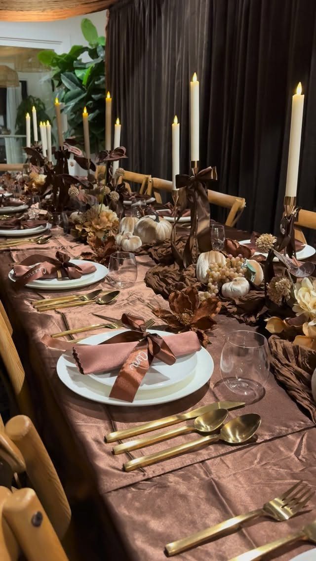 Formal autumn table setting with gold cutlery, white pumpkins, and tall white candles.