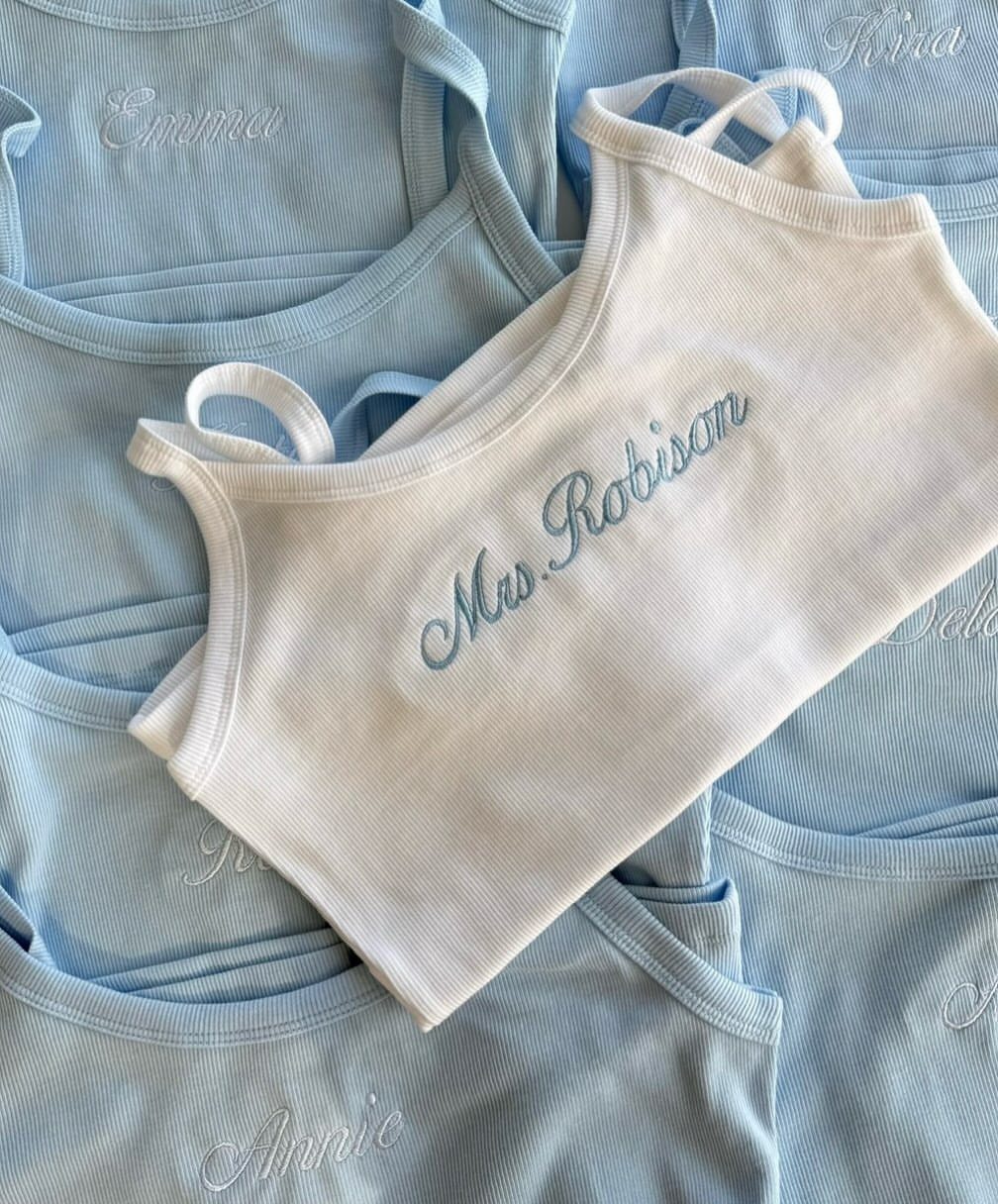 Ribbed camisole tops in white and light blue with personalized cursive embroidery.