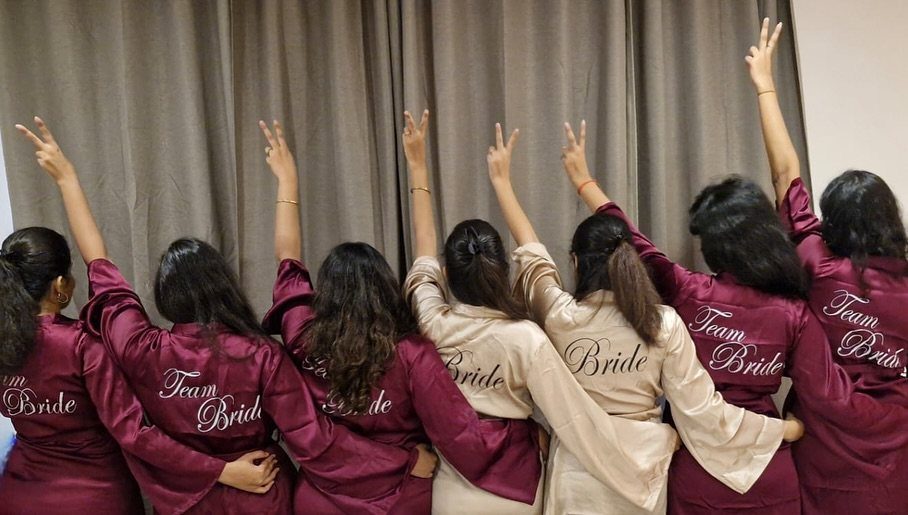 Women in satin robes posing with their backs to the camera in a room.