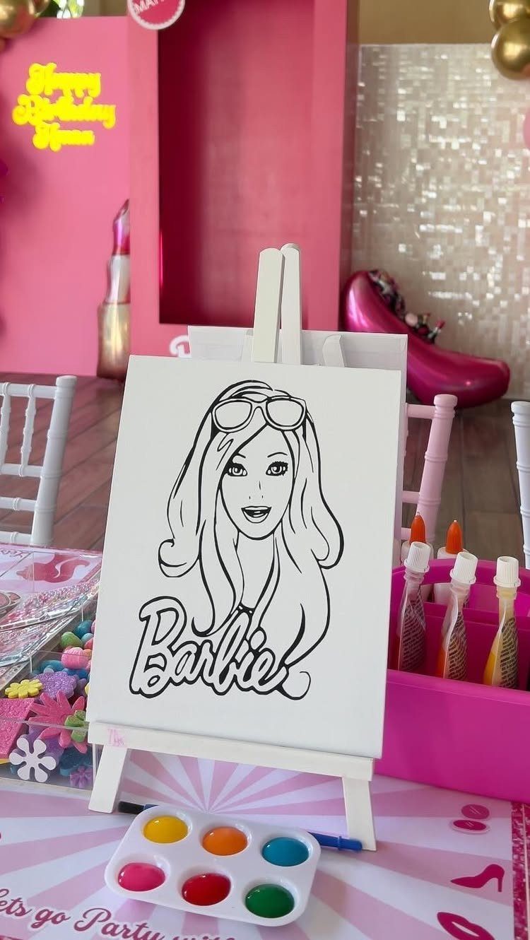 Barbie line drawing on a canvas easel with paint and glitter glue supplies.