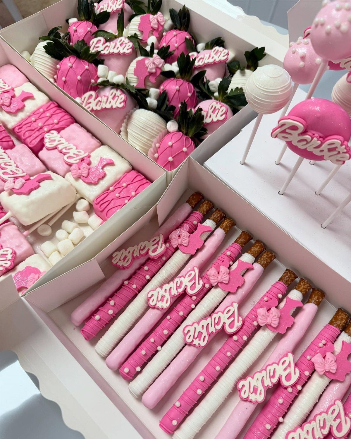 Pink and white Barbie themed treats including strawberries, marshmallows, and pretzel rods.
