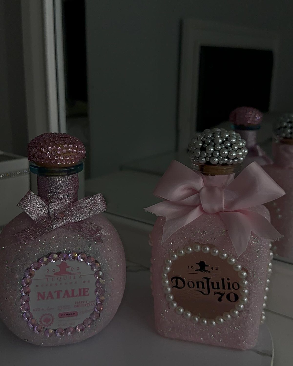 Glittery pink decorated bottles with bows and pearls for a themed party.