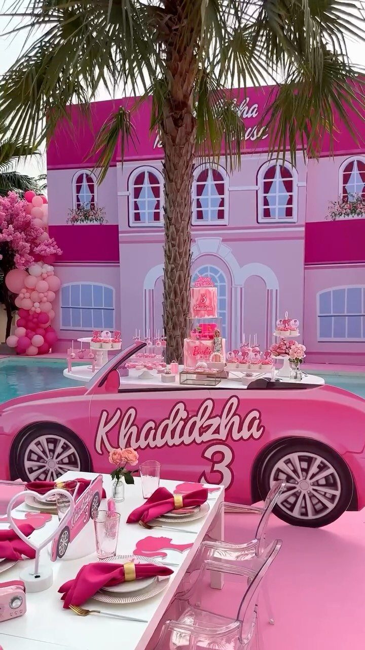 Pink Barbie themed birthday party setup with dollhouse backdrop and pink car cutout.