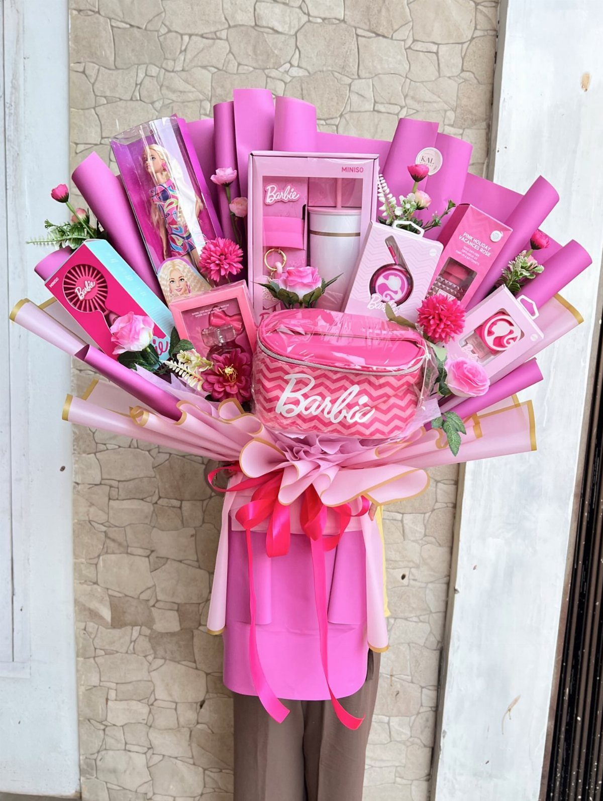 Barbie themed gift bouquet with doll, makeup bag, and beauty products in pink wrapping