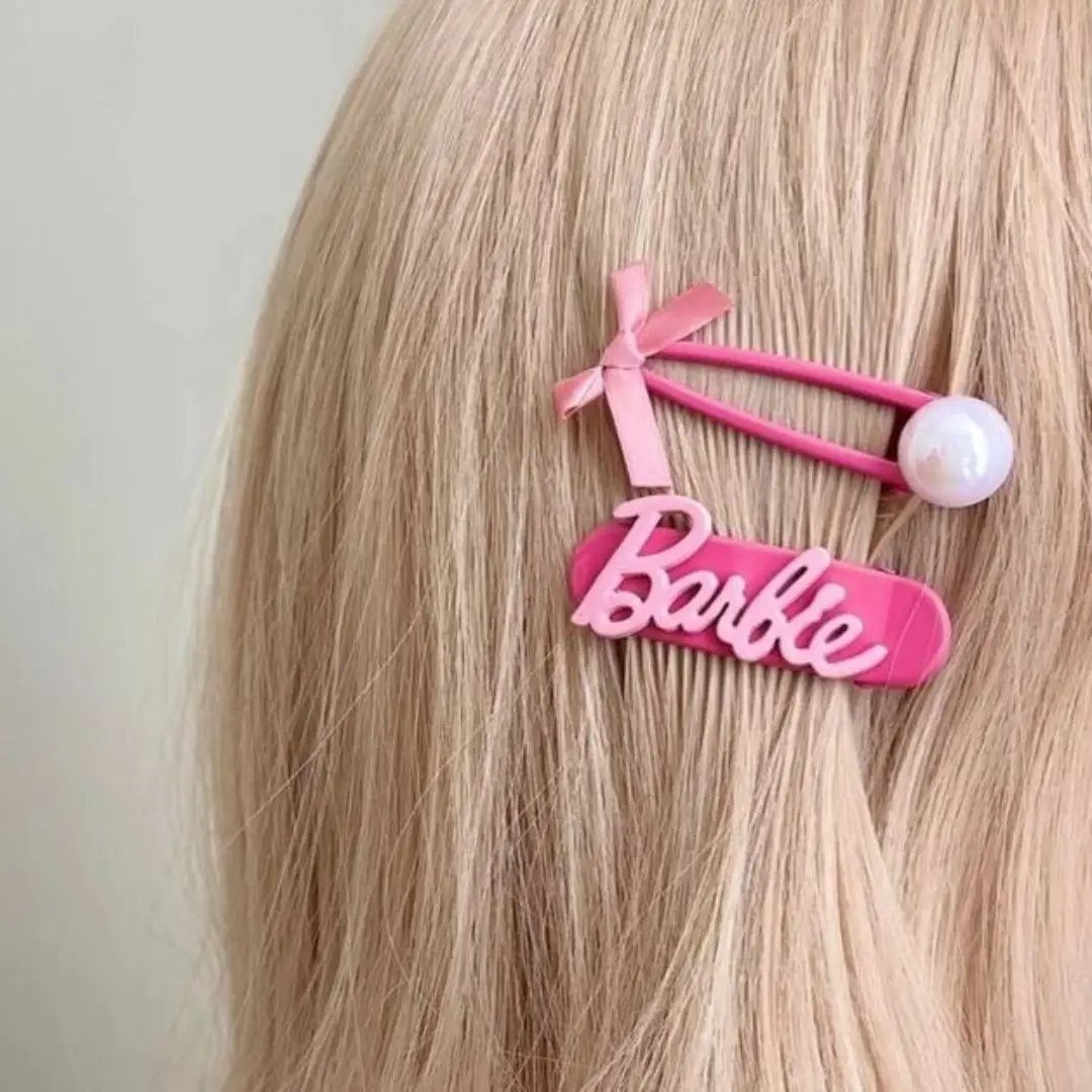 Pink Barbie hair clip with a bow and pearl in blonde hair