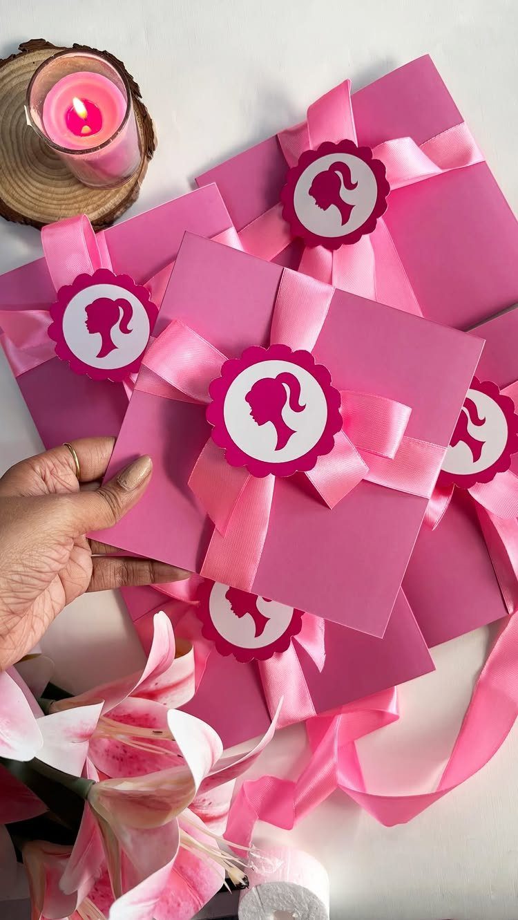 Pink square invitations tied with satin ribbons and Barbie silhouette stickers.