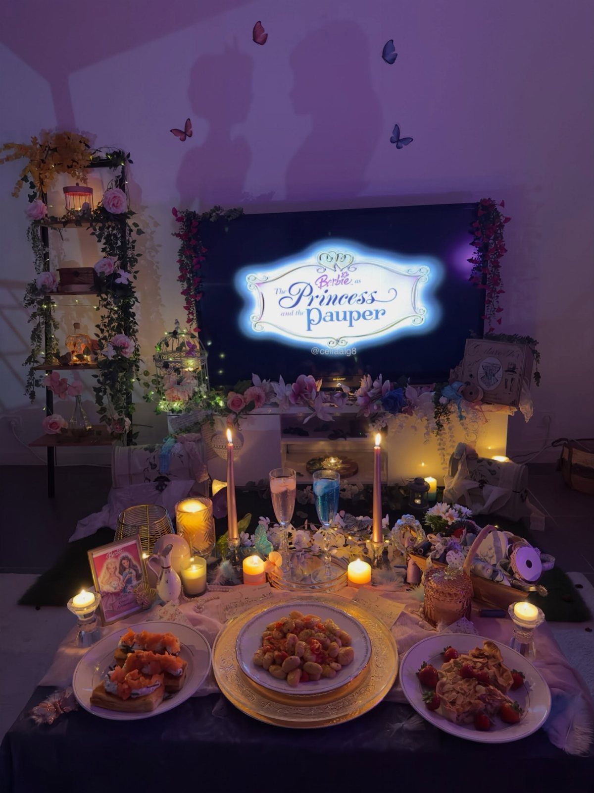 Television screen showing Barbie movie title surrounded by pink lights, candles, and food.