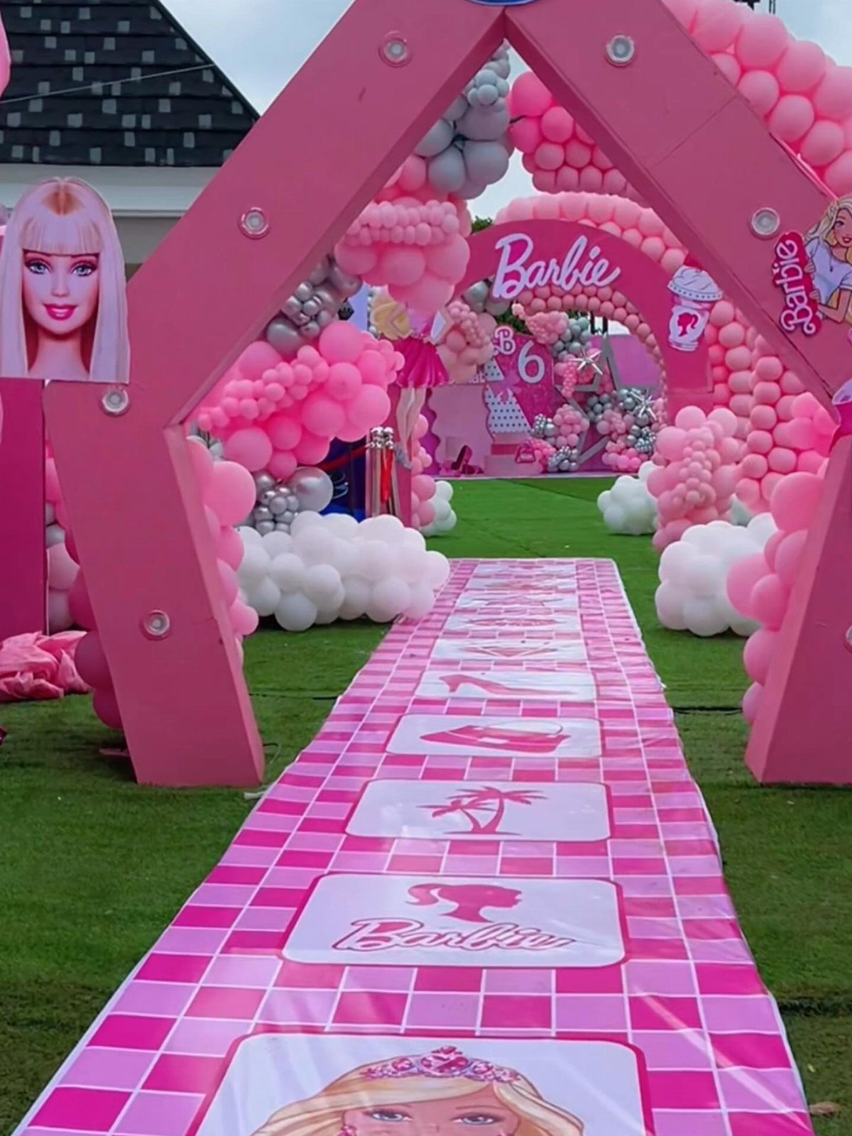 Pink checkered carpet runner with Barbie graphics leading through a balloon-decorated entrance.