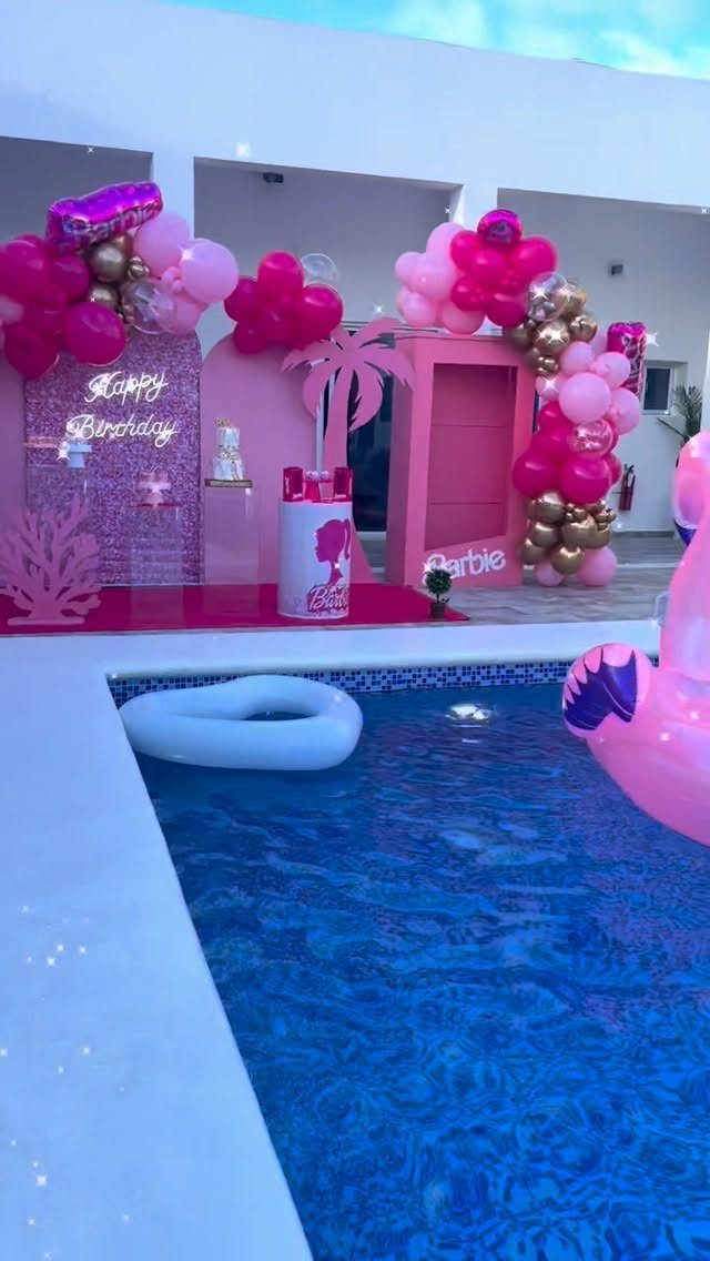 Barbie themed birthday party setup with pink balloons and decorations by a pool
