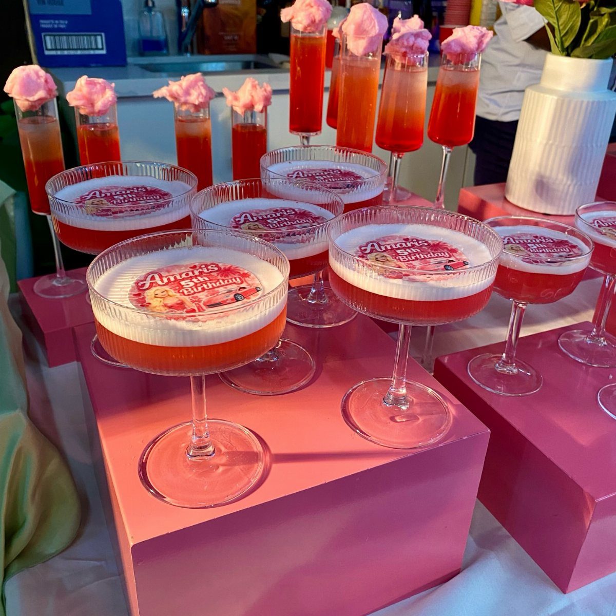 Pink and red themed drinks with cotton candy and edible toppers on pink pedestals